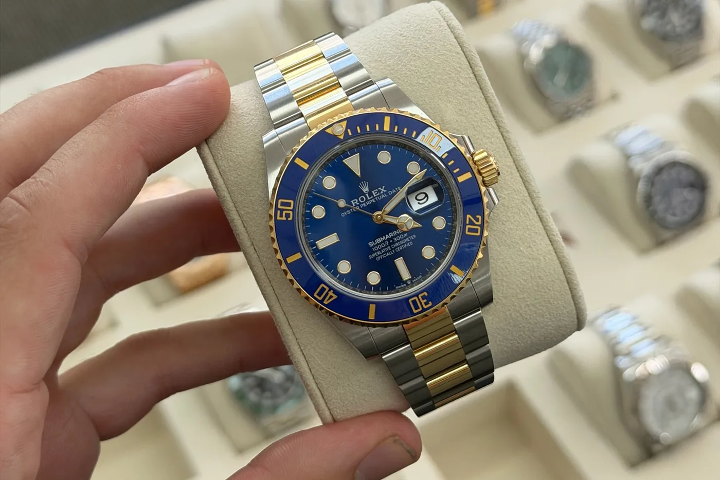 Rolex Submariner held above a tray of luxury watches in secure storage